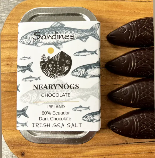 Sardines Dark Chocolate 60% (Tin Of 4), a tin of chocolate fish sitting on a wooden surface. 
