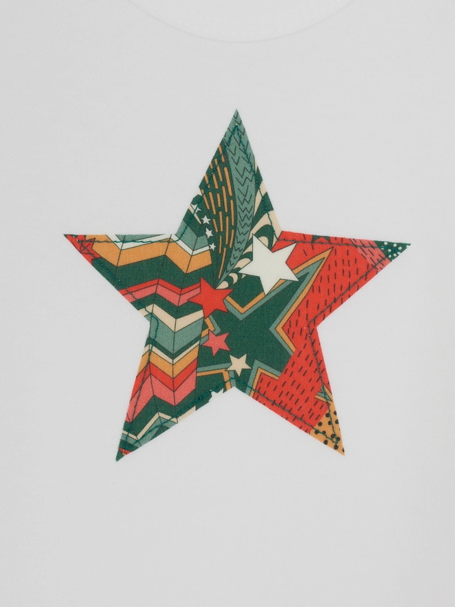 a christmas liberty print starry print star white bodysuit, close up on the appliqué stitching 