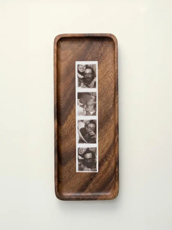 Walnut Photobooth Frame For Photo Strip Prints, hanging on a white wall. 