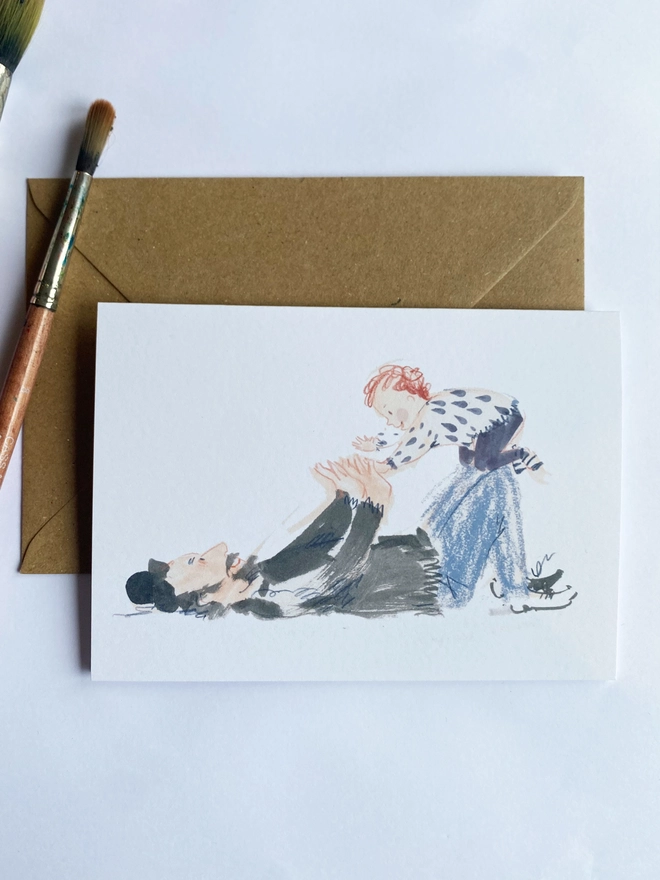 Esther Kent illustrated greetings cards showing a dad playing on the floor with child balancing on knees