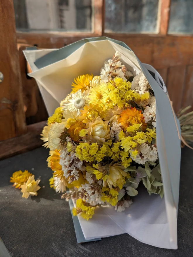 golden sunshine dried flower bouquet. bouquet of dried yellow flowers laid on a table.