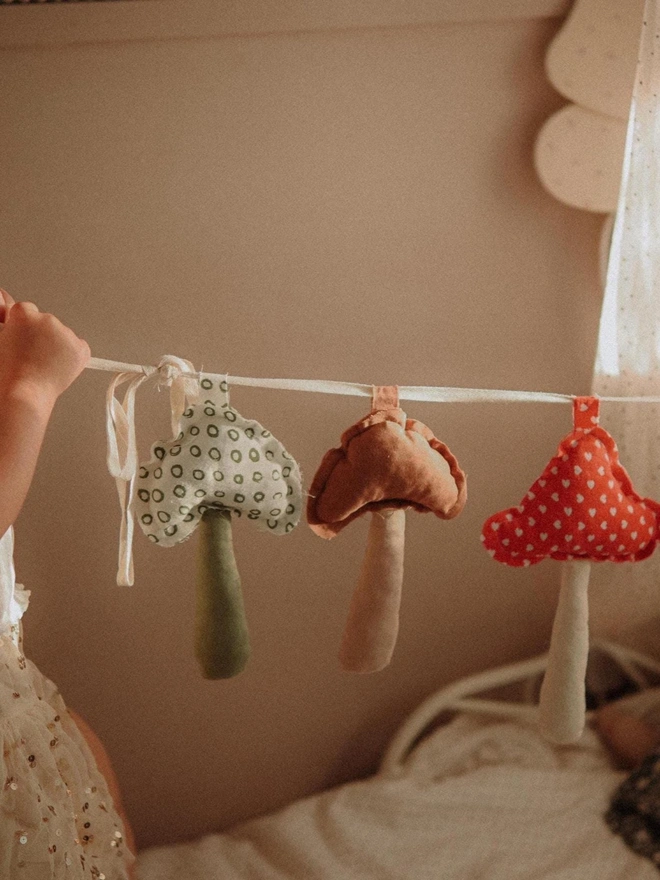 Mushroom Garland Decoration, a child playing with their hanging mushroom bunting in their bedroom.  