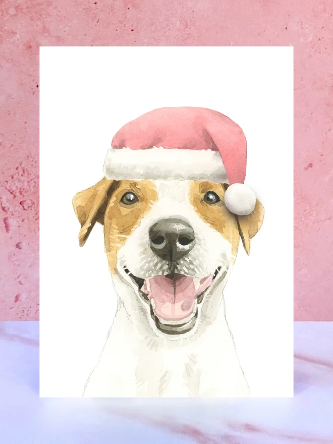 A Christmas card featuring a hand painted design of a jack russell terrier, stood upright on a marble surface. 