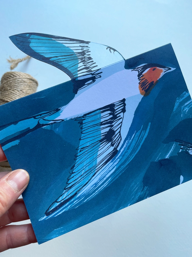 Esther Kent illustrated greeting card showing inky blue swallow illustration on a teal background. The swallow's wing pops u.