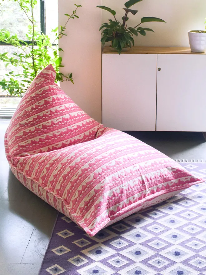 Pink Belle Mare Woven Bean Bag Cover, a pink bean bag sitting in a decorated room. It is accompanied by other colourful items. 