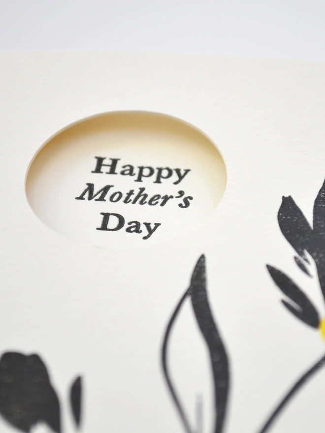 Close up image of Greeting Card with a cut out window in corner and Happy Mother's Day message inside.