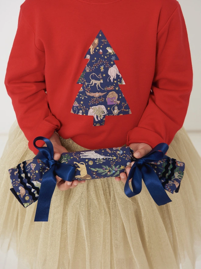 a 4 year old girl wearing a red t-shirt with a christmas tree cut from Liberty Christmas print sewn onto the front