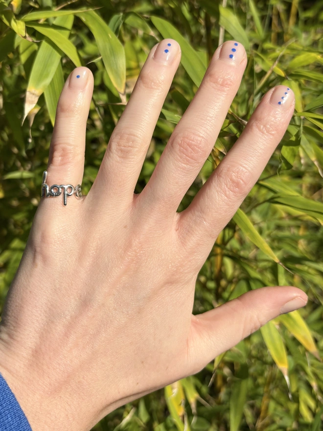 Small ring that says hope being worn on the little finger