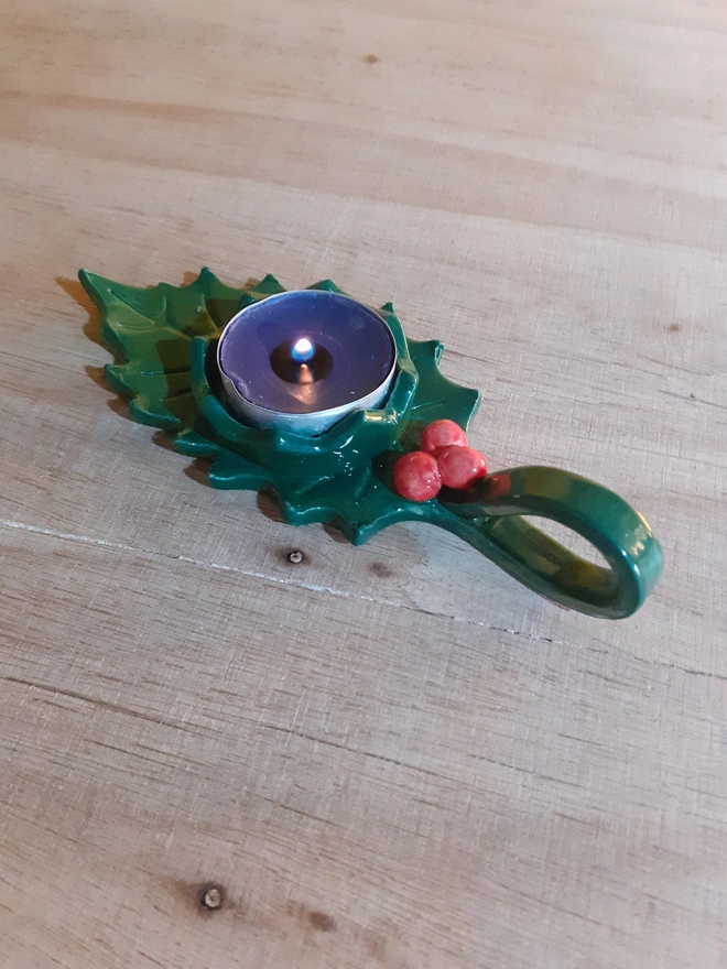 Christmas holly leaf candle holder handcrafted in glazed ceramic with handle and red berry detail.