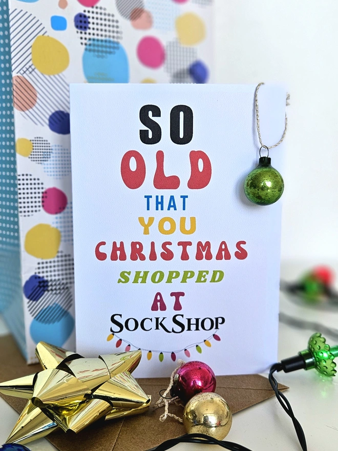 A photograph of the front of a humorous A6 greeting card illustrated using brightly coloured text and the retro shop logo. The text says so old you Christmas shopped at Sock Shop