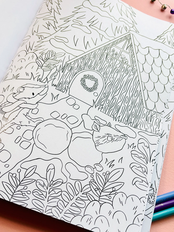 Woodland Christmas colouring book displayed with colouring pencils and winter decorations.