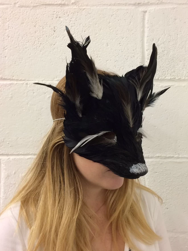 A woman wearing a luxury black fox masquerade mask down over her face