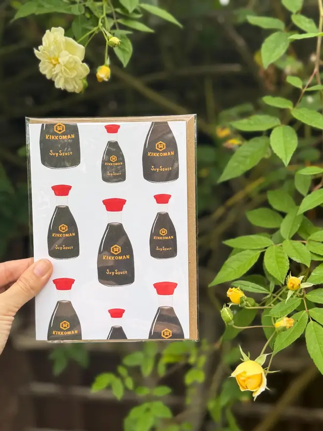 soy sauce bottles illustrated card. card photographed against rosebush backdrop.