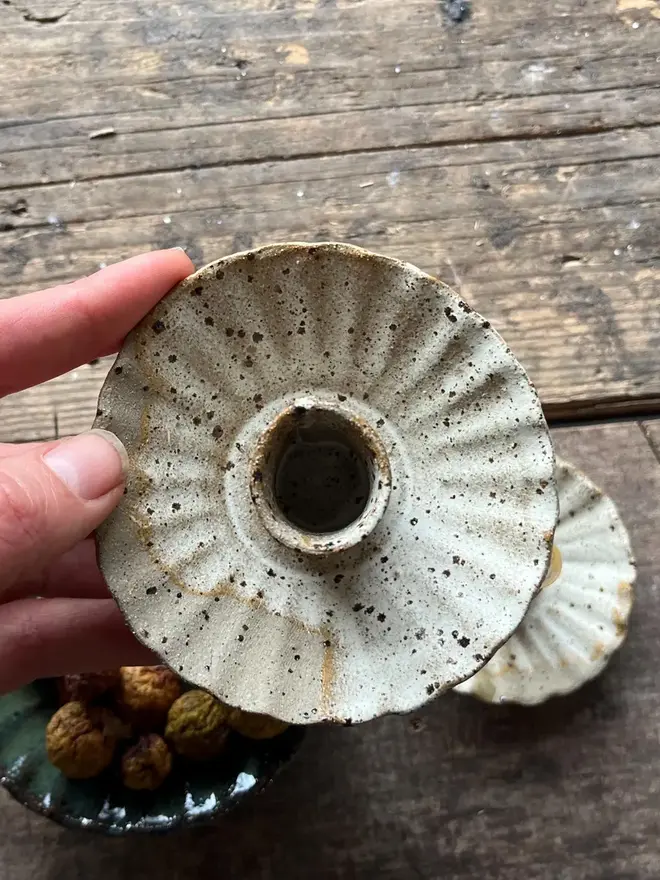 Handmade Natural Speckled Ceramic Candlestick Holder, a pair of ceramic candlestick holders sitting on a wooden surface. It is accompanied by a bowl of food. 