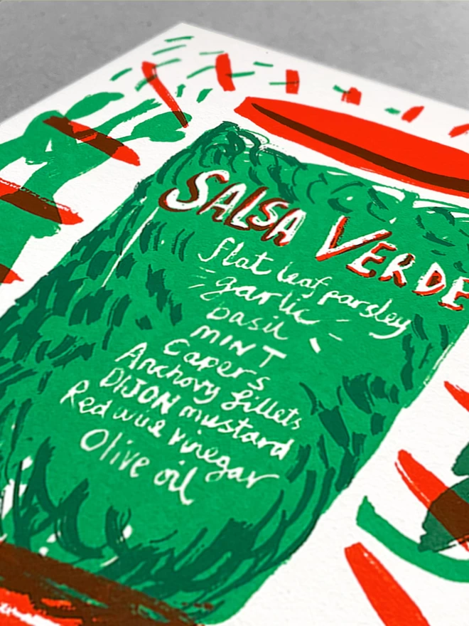 close up of A white card with a recipe for salsa verde, printed in green and red, a pot with a recipe written on it and then chopped ingredients around, and salsa dancers in the background. Card is sat in a light grey background.