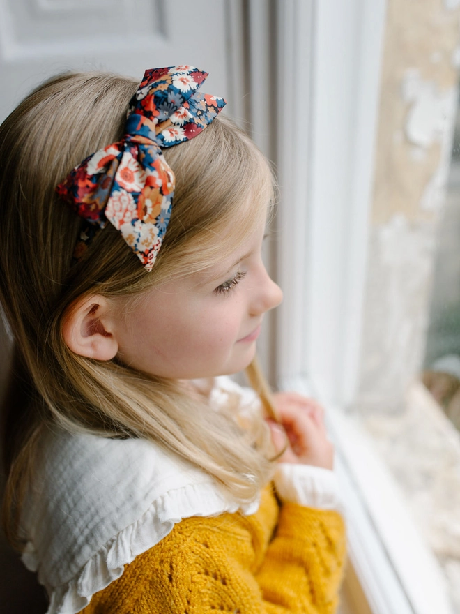 Girl looking out of window in her cardigan and lovely Liberty Alice Band