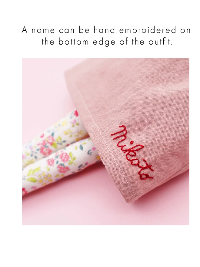 Personalised hand embroidery on a doll's pink dress.