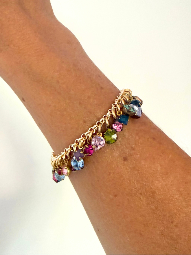 golden chain bracelet with rainbow jewel charms worn on wrist