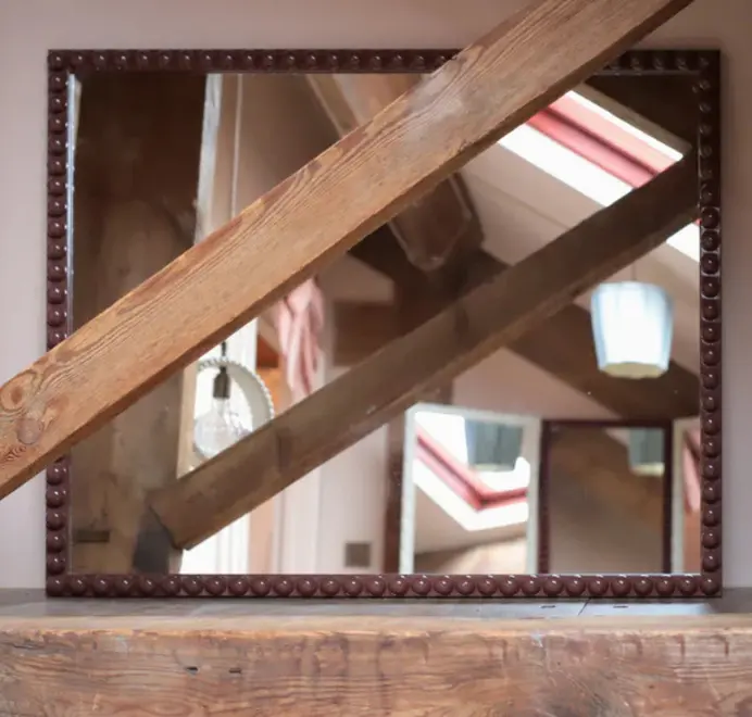 Over-sized bobbin mirror with a decorative turned-bead frame placed in a bedroom interior.