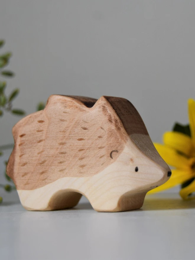 hedgehog wooden toy on shelf with flowers