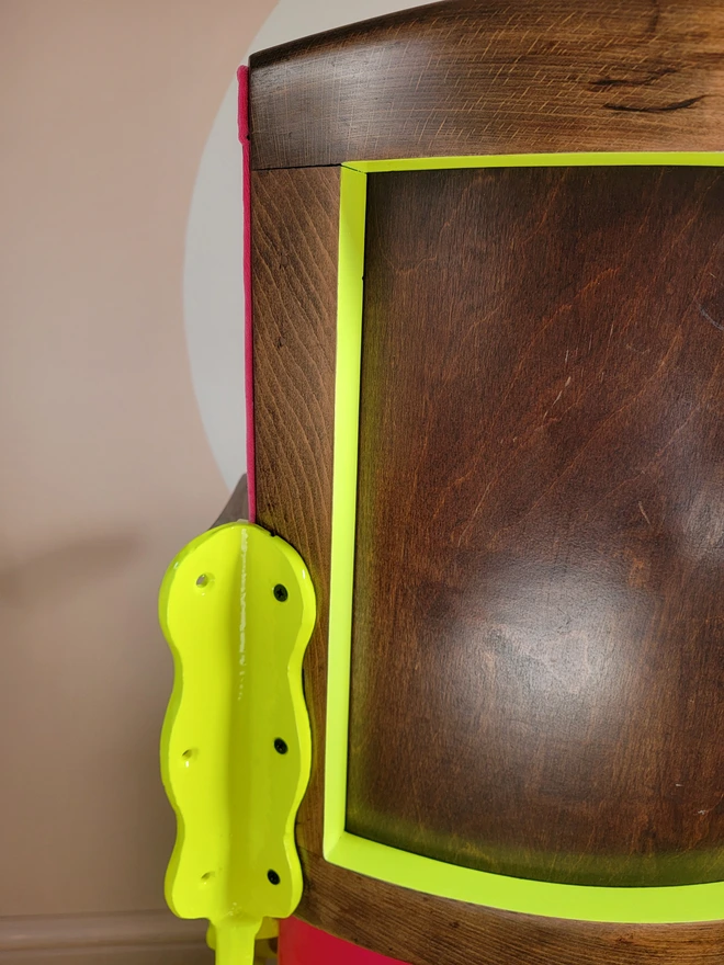 View of the wooden back of bright pink and neon yellow vintage cinema seat