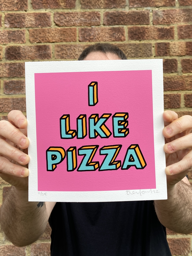 "I like Pizza" Mini Hand Pulled Screen Print square with pink background and the words i like pizza hand drawn and printed on top with black outline to the letters 