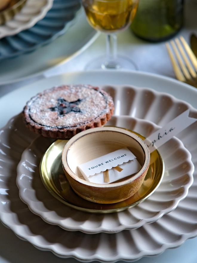 A festive handpainted wooden mince pie place setting with handwriten note to welcome your guests at the Christmas table