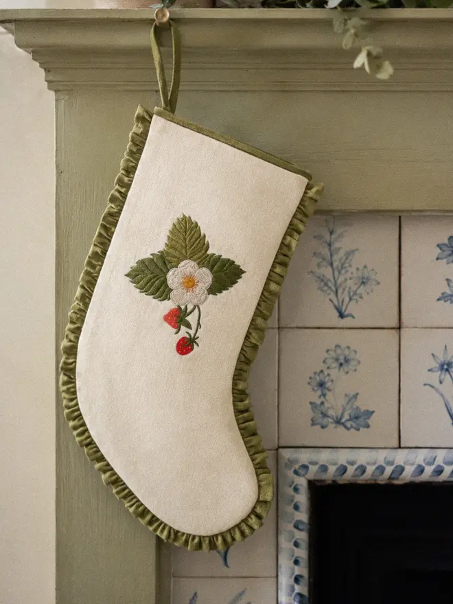 Strawberry Embroidery on an Ivory wool stocking with olive green linen frill. Style on a sage green wooden fireplace with floral antique tiles.