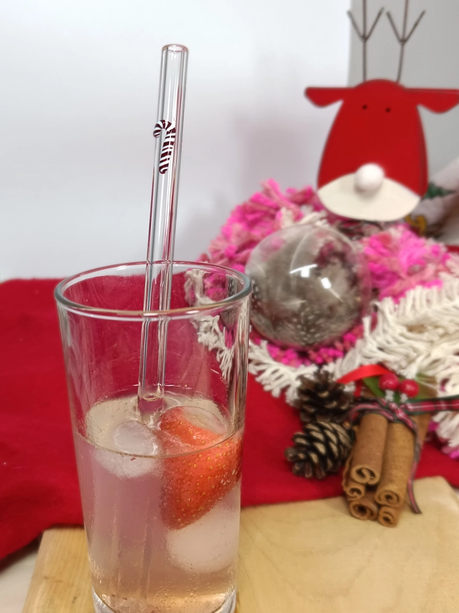 Candy cane straw inside a glass with a christmas layout