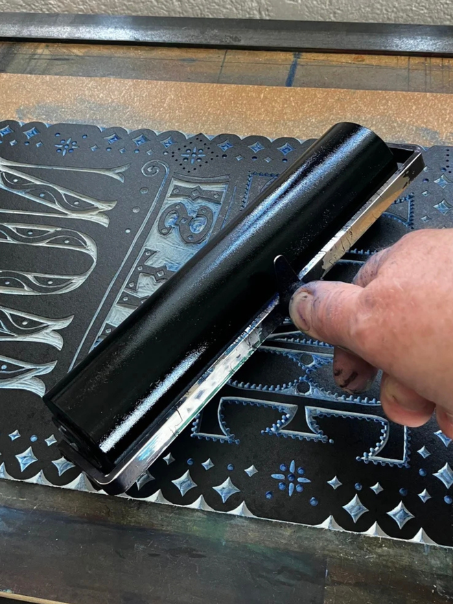 now is the time linocut. a linocut phrase printed on black paint.