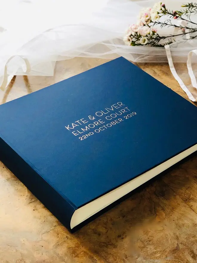 A Personalised Large Landscape Wedding Guest Book, positioned on a table next to flowers. 