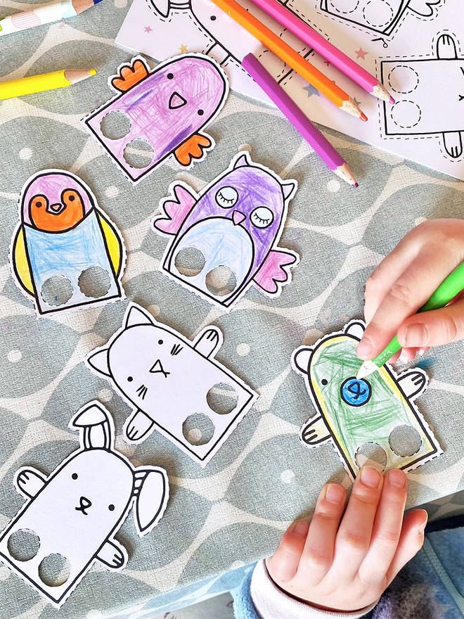 Several paper animal finger puppets are being coloured in by a small child.
