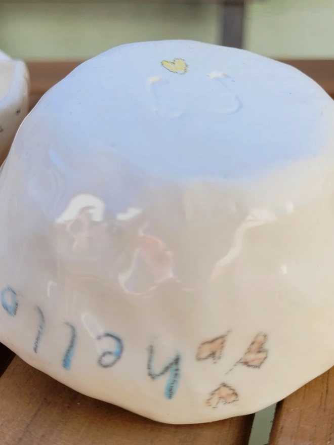 a close up of a small ceramic cream pot with the word hello and yellow heart on the base and 3 pink hearts on the side