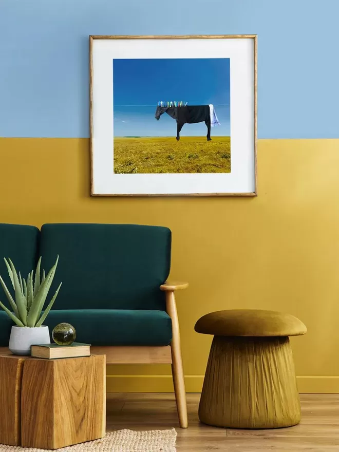 Pegasus the black clothesline horse hanging on a clothes line above a green field seen in a sitting room.