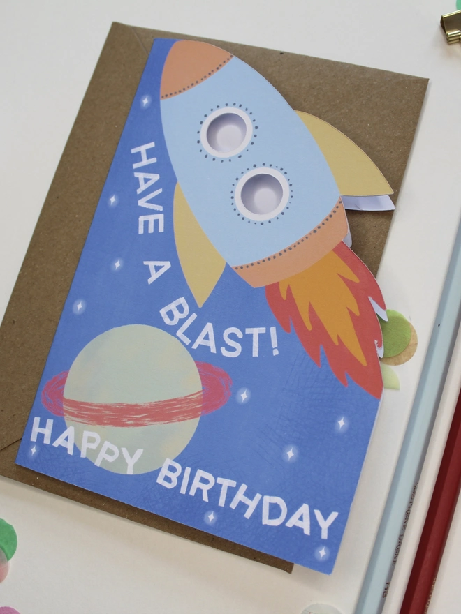 have a blast rocket birthday card. blue card with illustrated rocket and planets.