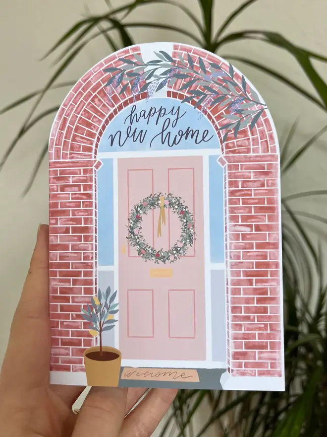 happy new home illustrated card. illustrated front of house with a wreath on the door.