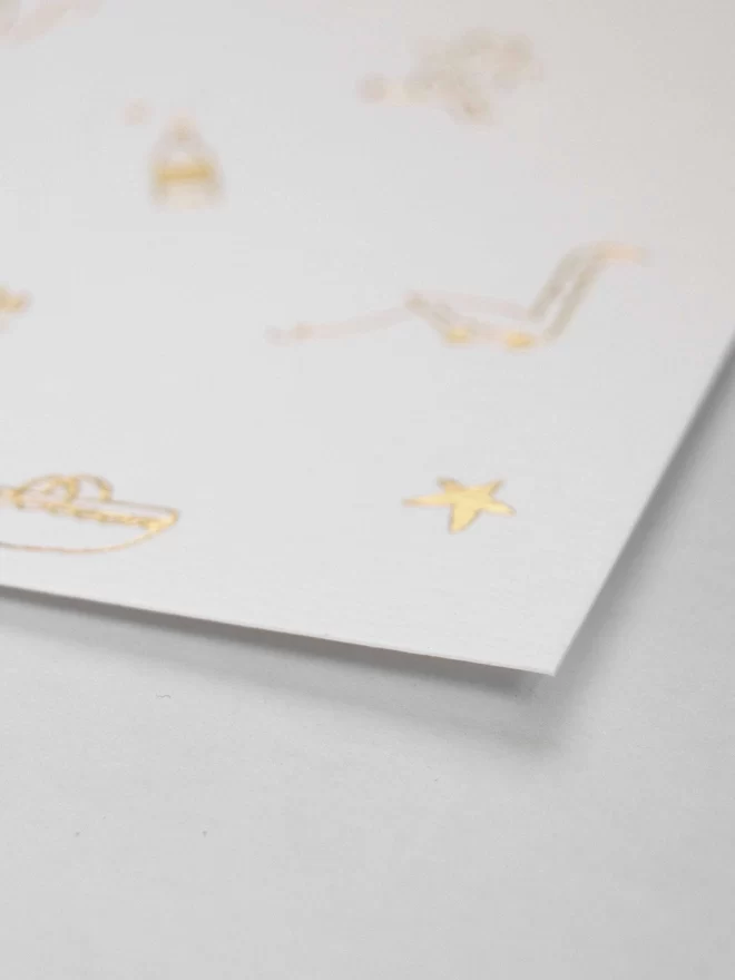 Front of A6 Gold foil new baby card. Linear doodle of baby associated icons. Close up.