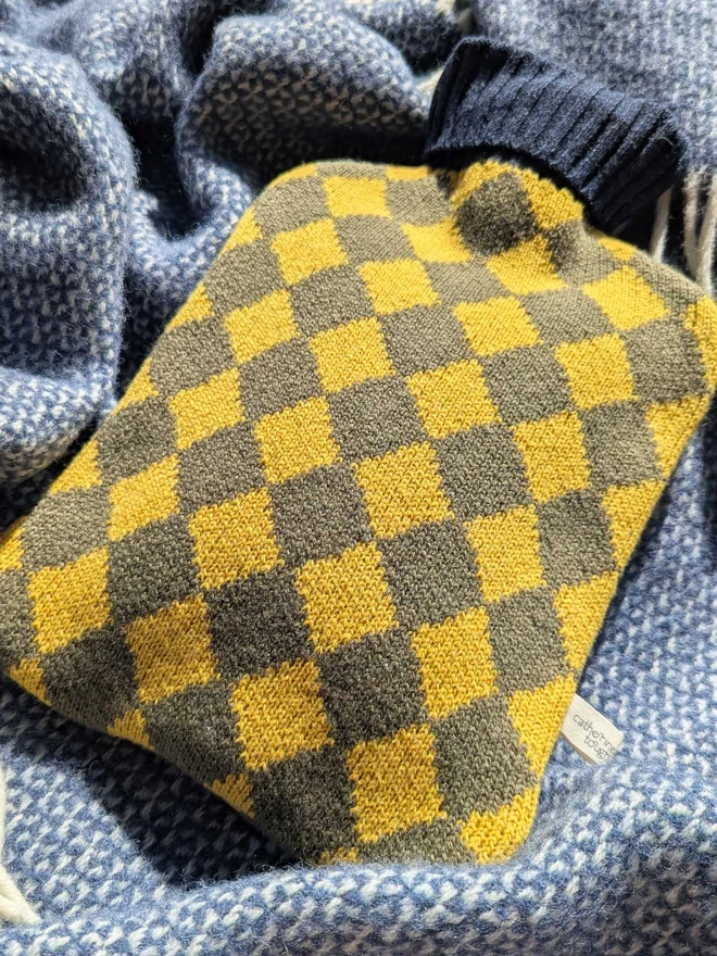 COLOURFUL HOT WATER BOTTLE COVER DISPLAYED ON A ON A BLANKET