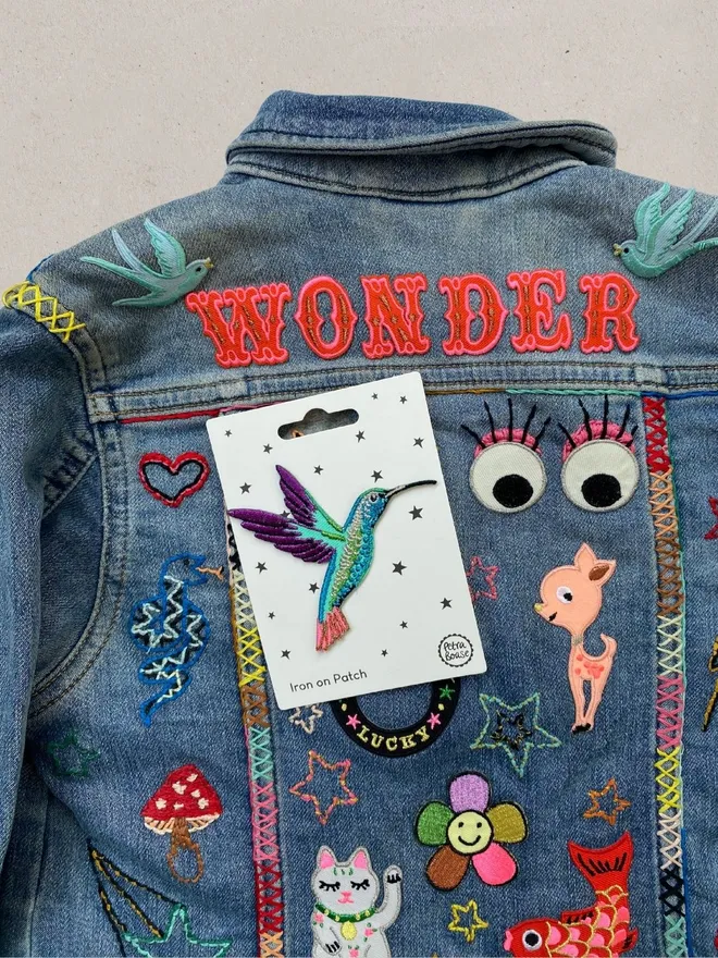Hummingbird patch on embroidered and patched denim jacket.