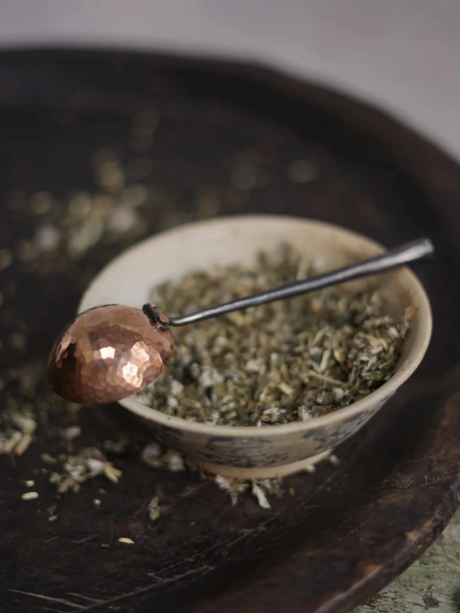 Copper And Stainless Steel Scoop, a metal scoop sitting on a bowl of herbs. 