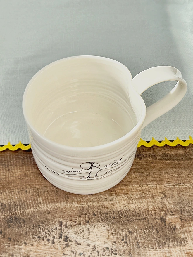 Handcrafted porcelain ‘Swim Wild’ mug – unique ceramic coffee cup for swimmers, nature lovers, and outdoor adventurers.
