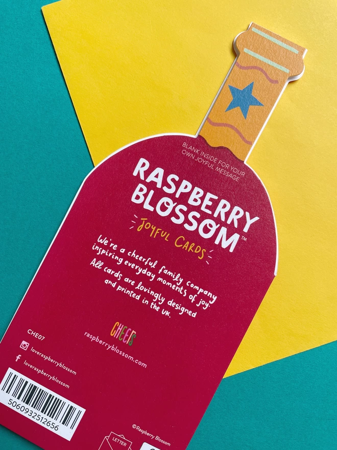 The reverse of the die cut wine shaped birthday card has a small blurb about Raspberry Blossom, a cheerful family company inspiring everyday moments of joy