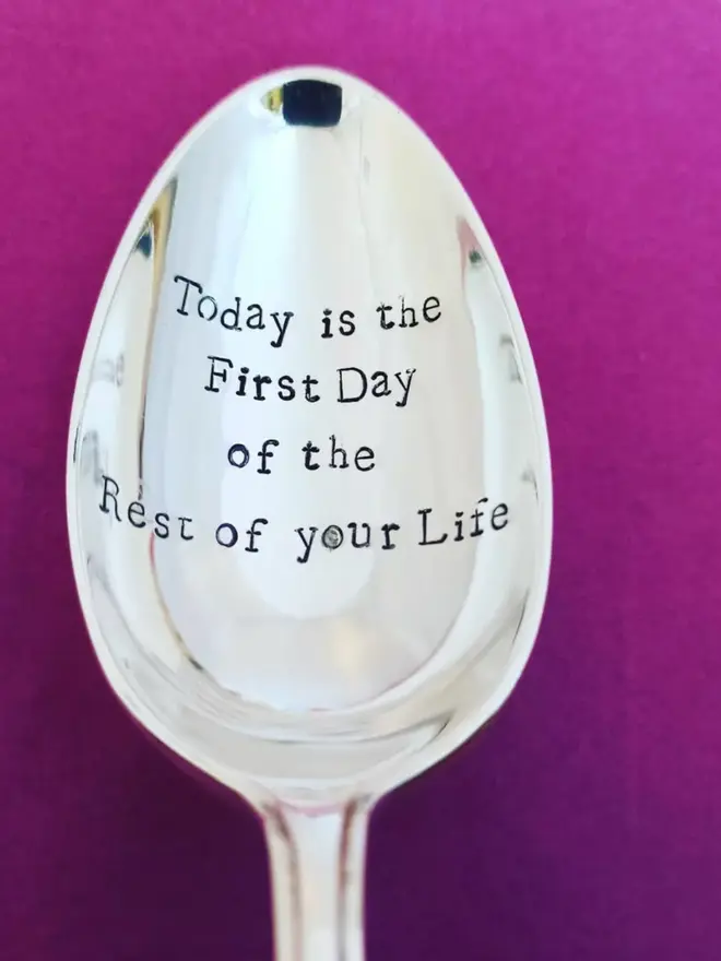 A vintage silver plated spoon hand stamped with the message Today is the First Day of the Rest of your Life. The spoons is on a purple background. 
