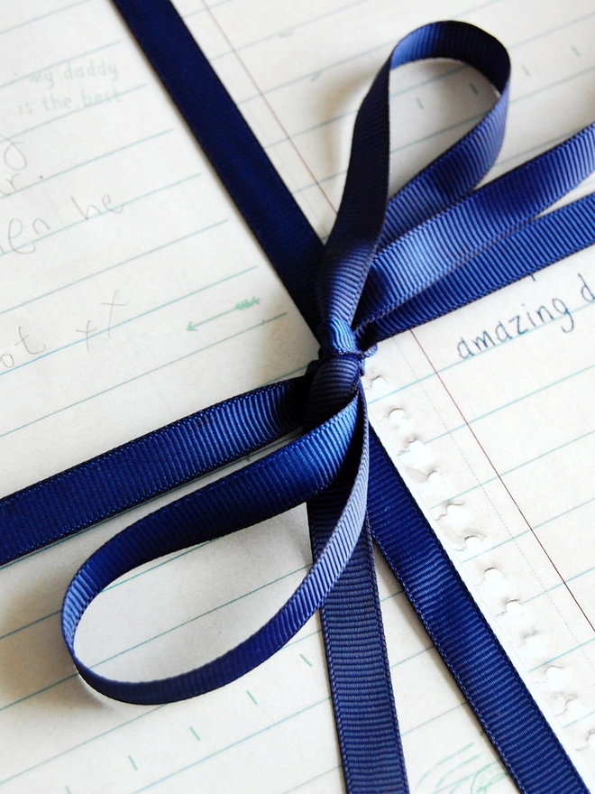 A gift wrapped in Daddy story wrapping paper, with spaces for children to write their own story to Daddy, is tied with a blue ribbon.