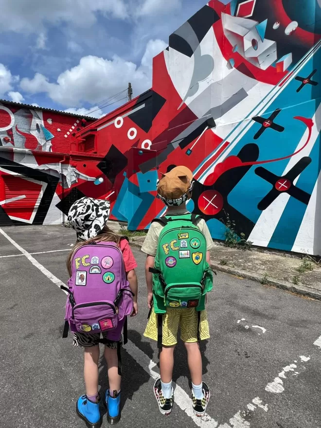 Two kids wearing the purple and green Beltbackpacks covered in Pachee patches.
