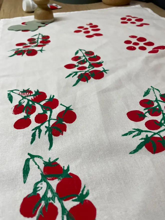 Tomatoes Kitchen Tea Towel. White fabric with a diagonal pattern of red tomatoes.