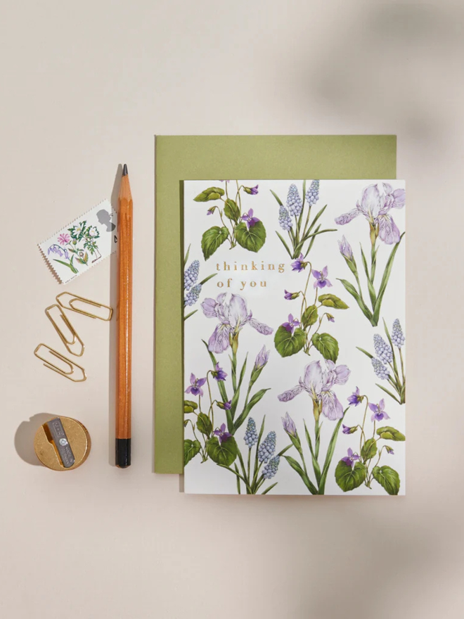 'thinking of you' illustrated floral card. a white floral card and green envelope photographed against a white background.