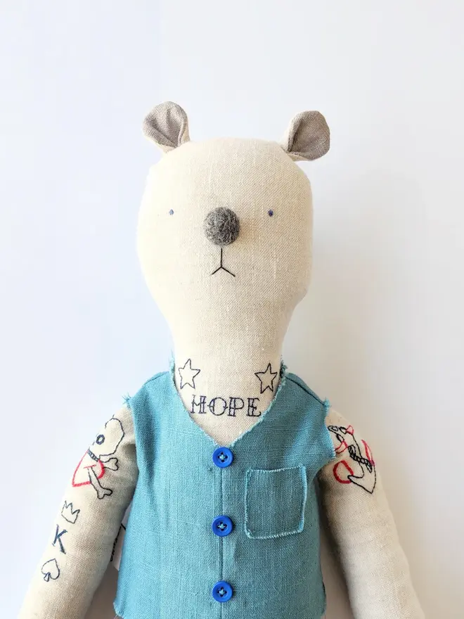tattooed bear doll. a cream linen bear doll with embroidered tattoos and a blue waistcoat.