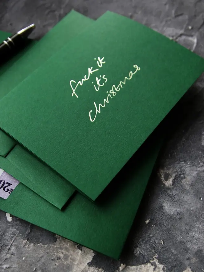 Hand foiled cash card or money wallet in a forest green colour handfoiled in shiny lime green text which says 'fuck it it's christmas'.