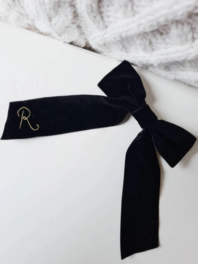 hand embroidered initials hair bow. a black hair bow with a gold R initial.